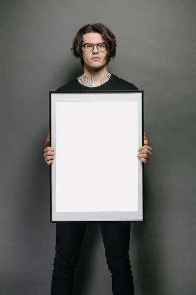 Hombre sosteniendo un marco de imagen o póster para maqueta con ropa negra — Foto de Stock