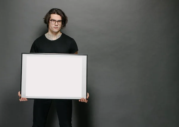 Hombre sosteniendo un marco de imagen o póster para maqueta con ropa negra —  Fotos de Stock