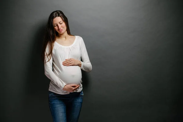 Terhes nő portré. Egy pocakot tart és mosolyog. — Stock Fotó