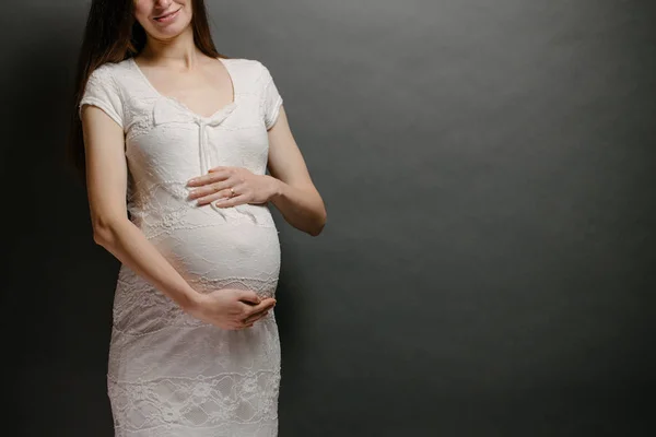 Gravid kvinna porträtt. Hon håller en mage och ler. — Stockfoto