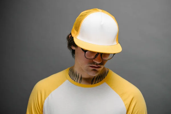 Hipster guapo modelo masculino con gorra de béisbol en blanco amarillo con espacio para su logotipo sobre fondo gris —  Fotos de Stock