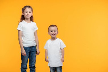 Çocuk ve kız beyaz tişörtler giyip logonuz için yer açtılar ya da sarı desenli tasarım yaptılar.