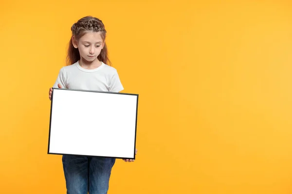 Niña sosteniendo cartel vacío o signo sobre fondo de papel amarillo —  Fotos de Stock