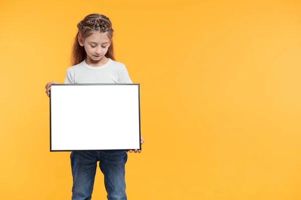 Niña sosteniendo cartel vacío o signo sobre fondo de papel amarillo — Foto de Stock