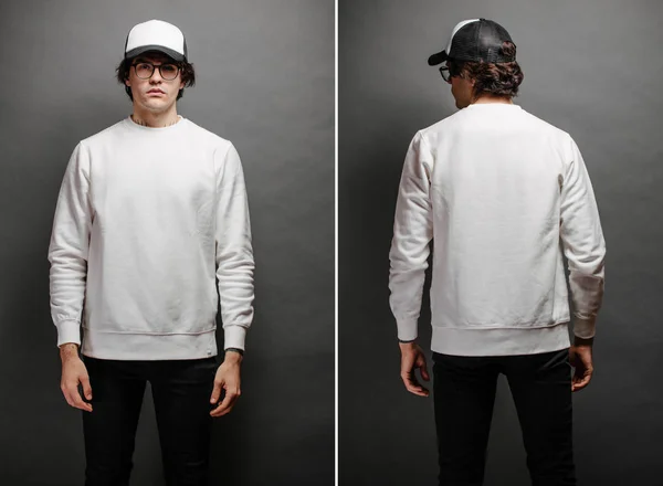 Hombre con sudadera blanca en blanco y gorra de béisbol vacía de pie sobre fondo gris. Sudadera o sudadera con capucha para maqueta, diseños de logotipo o impresión de diseño con espacio libre. — Foto de Stock