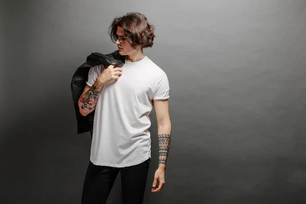 Hipster όμορφο ανδρικό μοντέλο με γυαλιά που φορούν λευκό κενό t-shirt και μαύρο τζιν με χώρο για το λογότυπο ή το σχέδιό σας σε casual urban στυλ — Φωτογραφία Αρχείου