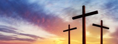 Cross of Jesus Christ empty over dramatic sunrise sky panorama w clipart