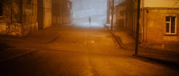 Einsame Frau spaziert in nebliger Altstadt mit Straßenlaterne im Mantel — Stockfoto