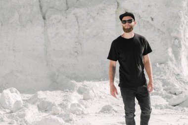 Sakallı, siyah, boş tişörtlü, beysbol şapkalı, logonuz için yeri olan yakışıklı bir hippi mankeni.