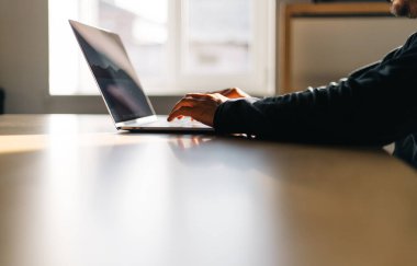 Ofis çalışma alanı. Ahşap masanın üstünde dizüstü bilgisayarda çalışan bir adamla masa.