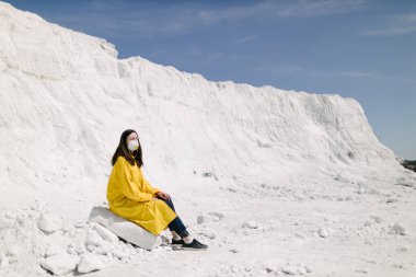 Kimyasal bitki atıklarının oluşturduğu fosfat dağında yürüyen genç bir kadın. Sarı koruyucu ceket ve maske giyiyor. Ekoloji koruma farkındalığı