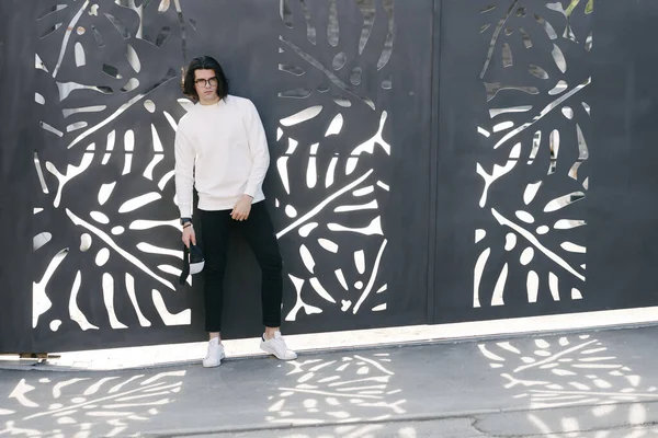 Man wearing white sweatshirt or hoodie and glasses outside on the city streets. Sweatshirt or hoodie for mock up, logo designs or design prints with free space