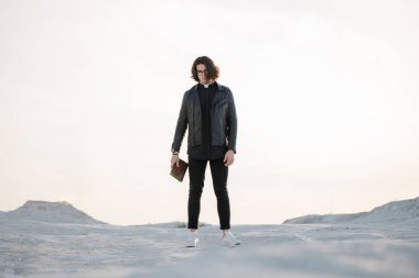 Gün batımında genç ve yakışıklı bir rahip portresi. Gözlüklü, Roma yakalı ve deri ceketli..