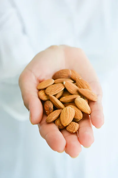 Female hand holding pile of almonds — Stock Photo, Image