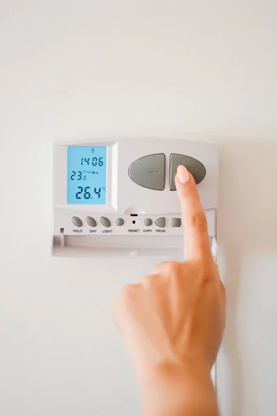 Ajuste a temperatura com o termostato no interior da casa — Fotografia de Stock