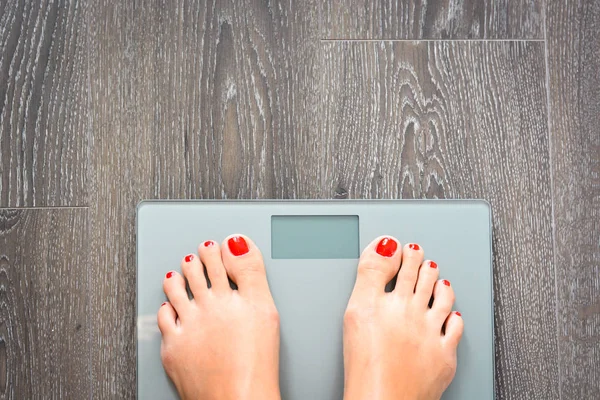 Concepto de dieta con pies de mujer en una balanza, ponderándose a sí misma — Foto de Stock