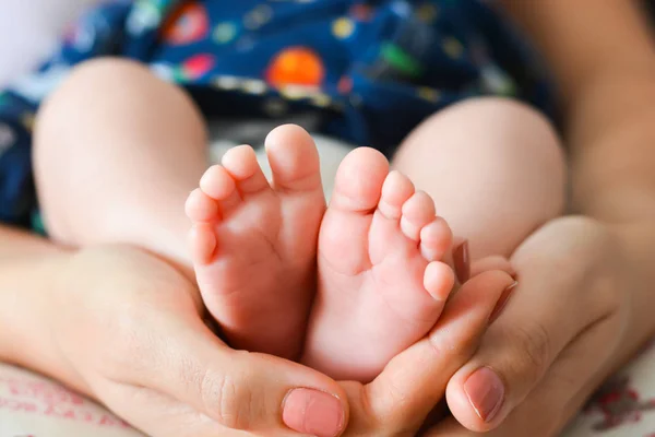 Young mother holding newborn baby foot in her palms — Stock Photo, Image