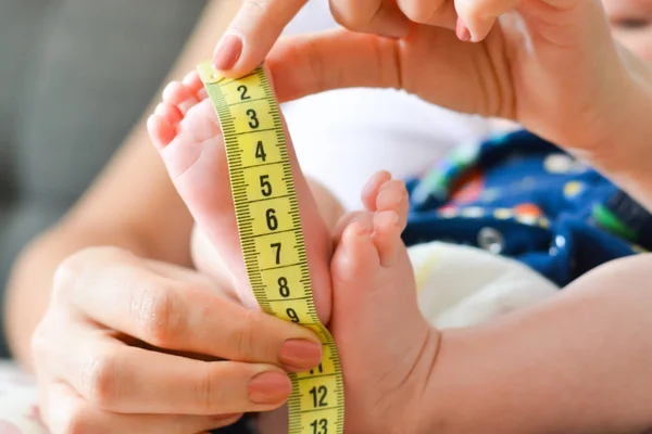 Mother measuring tiny baby foot with a meter