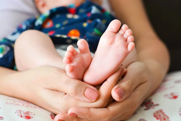 Young mother holding newborn baby foot in her palms — Stock Photo, Image