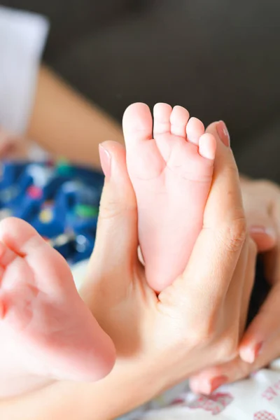 Young mother holding newborn baby foot in her palms — Stock Photo, Image