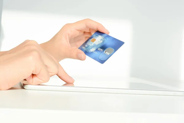 Крупный план женской руки, держащей синюю кредитную карту с помощью мобильного устройства для онлайн-покупок — стоковое фото