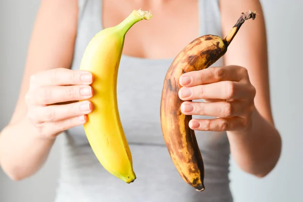 Bananas frescas e maduras demais na mão da mulher — Fotografia de Stock