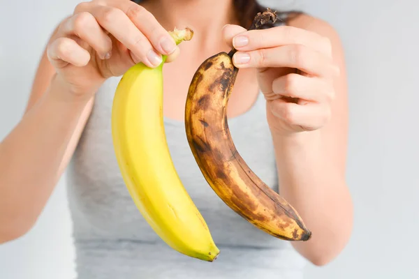 Bananas frescas e maduras demais na mão da mulher — Fotografia de Stock