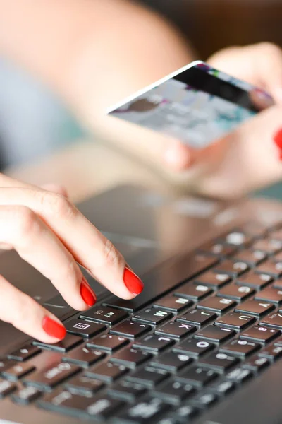 Primer plano de la mano de la mujer sosteniendo una tarjeta de crédito azul utilizando un ordenador portátil para las compras en línea — Foto de Stock