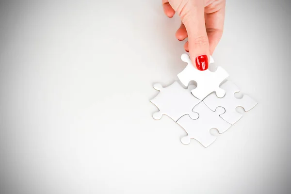 Mujer de la mano que se ajusta a la pieza derecha del rompecabezas sugiriendo concepto de red de negocios — Foto de Stock