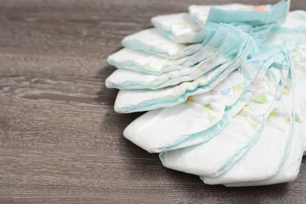 Pile or stack of baby diapers isolated on wooden floor — Stock Photo, Image