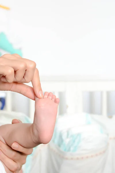 Young mother holding newborn baby foot in her palms — Stock Photo, Image