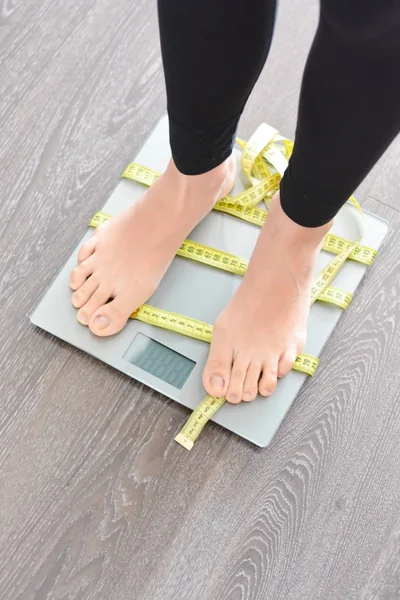 Teyp ölçme ile kadın ayakları ağırlık ölçek üzerinde sarılı — Stok fotoğraf