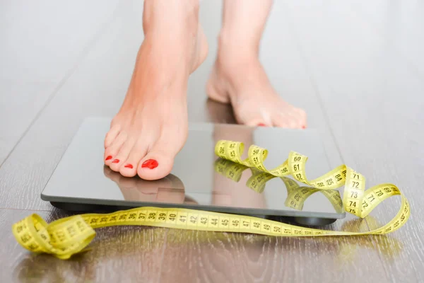 Help to lose kilograms with woman feet stepping on a weight scale — Stock Photo, Image