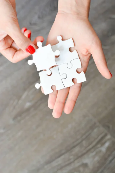 Vrouw hand montage van de juiste stuk puzzel suggereert netwerken bedrijfsconcept — Stockfoto