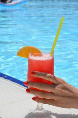 Bir yüzme havuzu bir kokteyl tutan el
