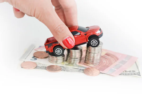 Vrouw hand duwen een speelgoedauto over een stapel van munten — Stockfoto