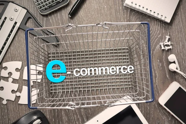 Conceito de comércio eletrônico com cesta metálica de compras cercada por dispositivos eletrônicos — Fotografia de Stock