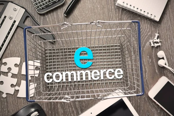 Conceito de comércio eletrônico com cesta metálica de compras cercada por dispositivos eletrônicos — Fotografia de Stock