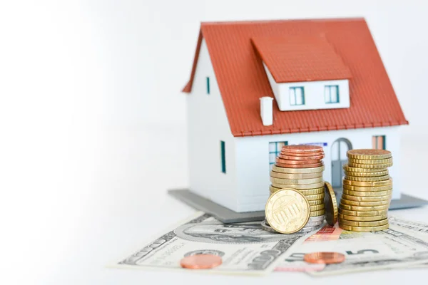 Klassiek huis model met stapel van munten geïsoleerd op witte achtergrond — Stockfoto