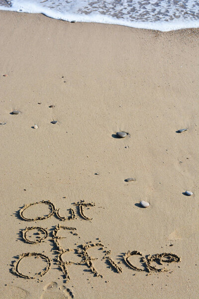 Out of office text written on the beach 
