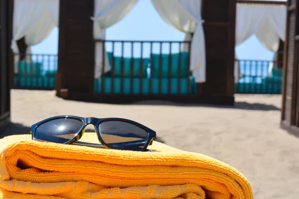 Γυαλιά ηλίου και μια πετσέτα στην παραλία — Φωτογραφία Αρχείου