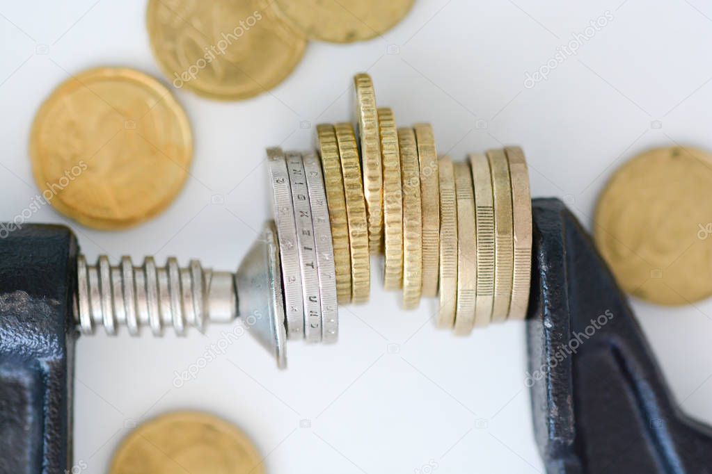 Economy pressure concept with stack of coins in a cramp