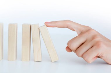 Human hand starting a domino effect concept with wooden blocks clipart