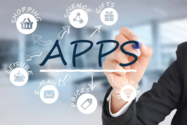 Geschäftsfrau schreibt das Wort Apps mit einem Marker auf einen transparenten Bildschirm, wobei sich App-Symbole vom Hauptwort ausbreiten — Stockfoto