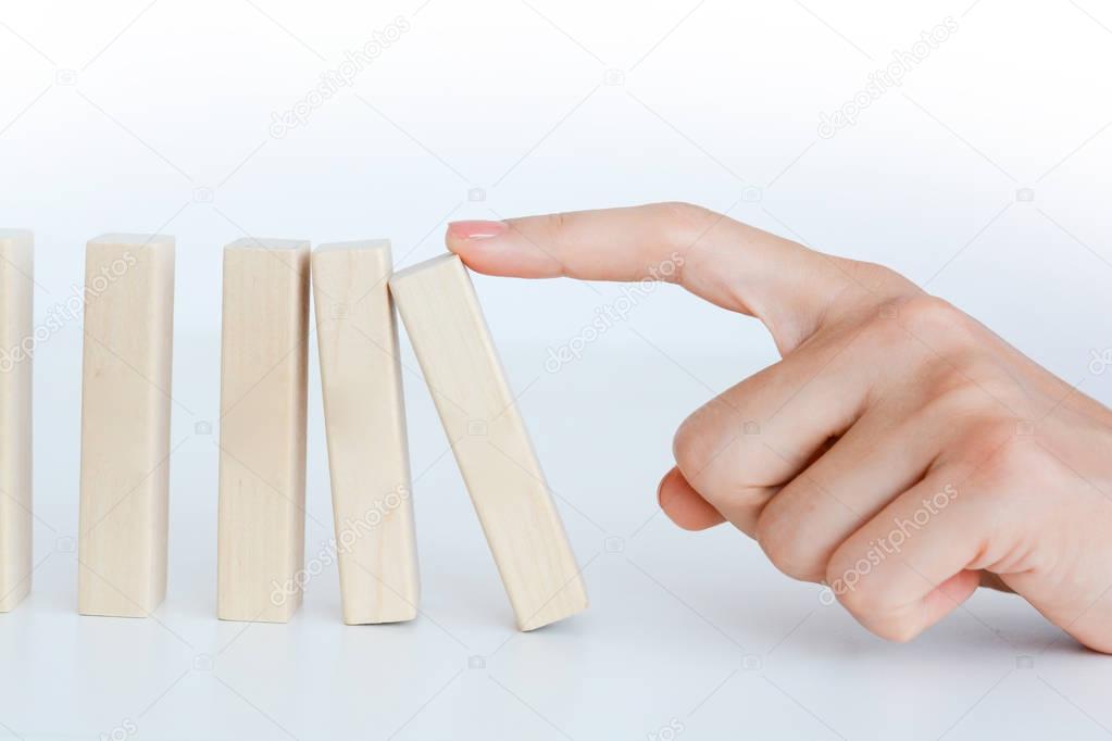 Human hand starting a domino effect concept with wooden blocks