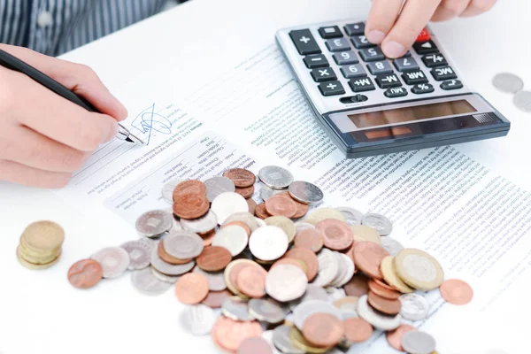 Beräkning av skatt eller nytt låneavtal med handen miniräknare och mynt — Stockfoto