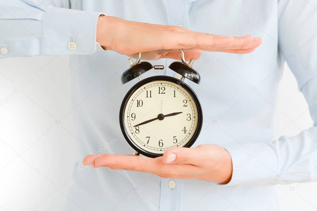 Businesswoman holding an old clock in hands suggesting deadline concept