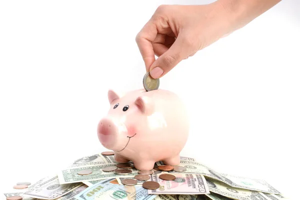 Woman hand putting money in a pink piggy bank standing on money pile — Stock Photo, Image