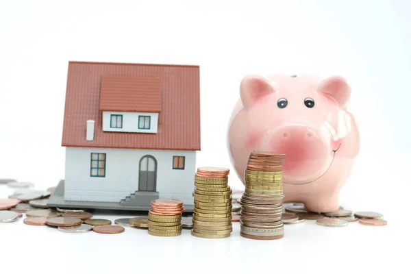 Hucha y casa modelo en efectivo sugiriendo ahorros para la casa — Foto de Stock