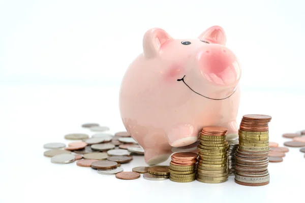 Pink piggy bank standing on coins, suggesting money savings concept — Stock Photo, Image